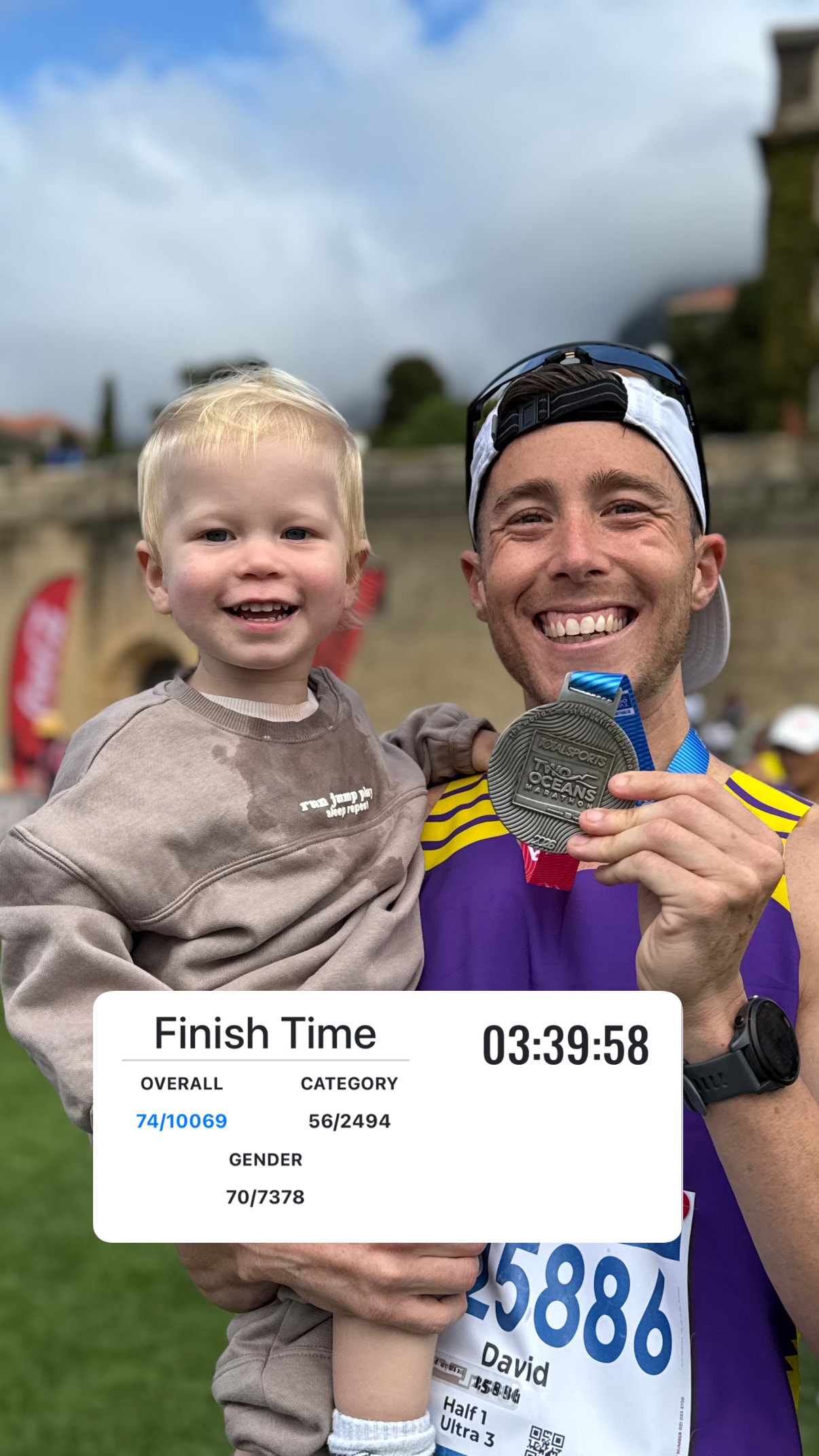 David Fick with his child after the Two Oceans Marathon, showing his finish time of 03:39:58